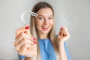 Woman with manicured hand holding Invisalign aligner