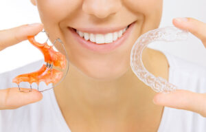 Patient putting in their retainer after Invisalign treatment